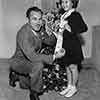 Shirley Temple receiving her Rose Parade Grand Marshal ribbon from Tournament Chairman Lathrop K. Leishman at her Fox Bungalow, November 21, 1938
