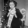 Shirley Temple receiving her Rose Parade Grand Marshal ribbon at her Fox Bungalow, November 21, 1938